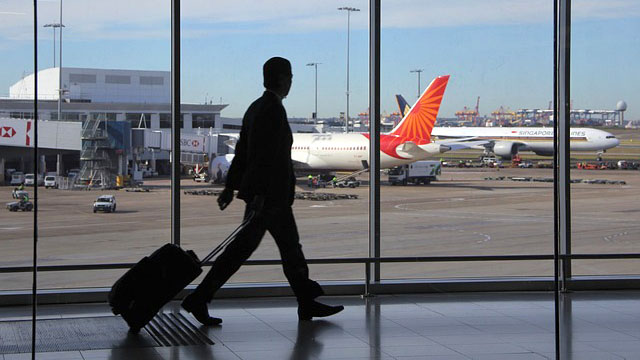 A man walking in an airport with his suitcase